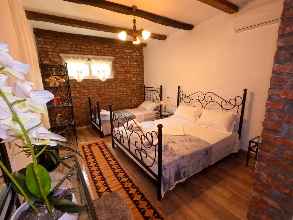 a bedroom with two beds and a brick wall at InTown Guesthouse Shkoder in Shkodër