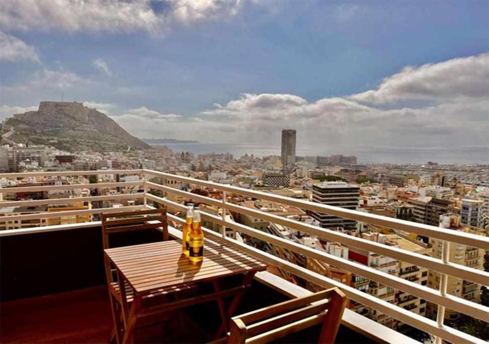 a table on a balcony with a view of a city at Suites Alicante in Alicante