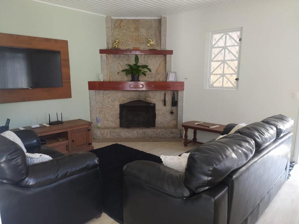 sala de estar con sofá de cuero y chimenea en Casa aconchegante com lareira en Campos do Jordão