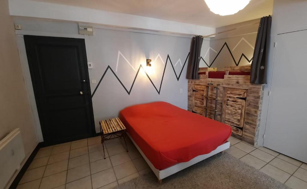 1 dormitorio con cama roja y puerta negra en Un petit studio à la montagne, en Ax-les-Thermes