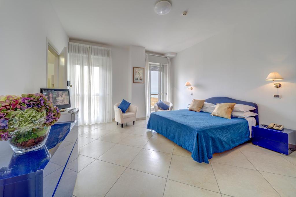 1 dormitorio con 1 cama azul y sala de estar en Hotel Carlton Beach, en Rímini