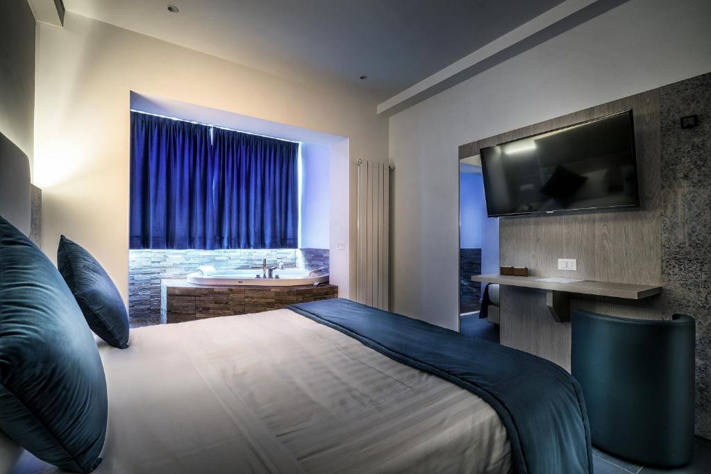 a bedroom with a bed and a tub and a television at Suite Blue Style in Rome