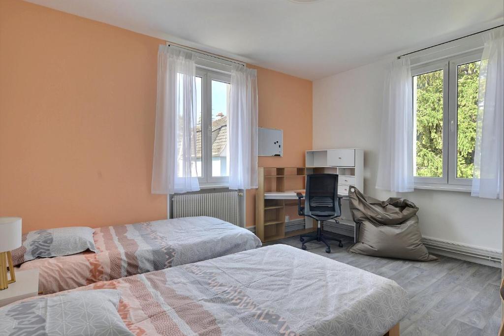 a bedroom with two beds and a desk and two windows at "Urbaine Colors" Appartement coloré et lumineux "Les Péri-Urbaines" in Riedisheim