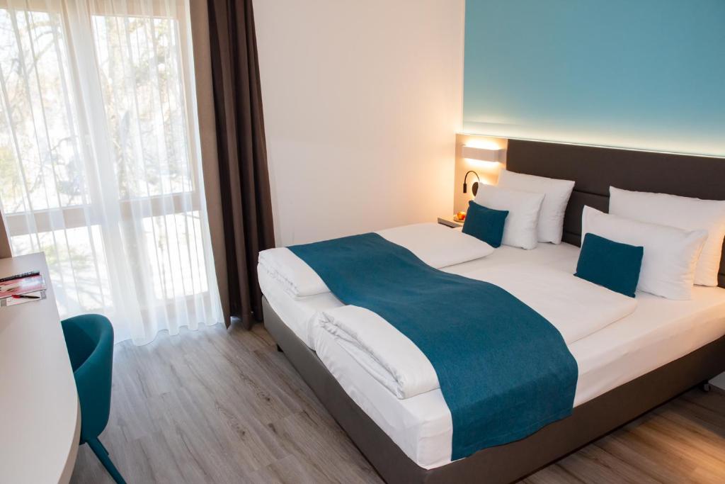 a bedroom with a large bed with a blue blanket at Hotel Kapuzinerhof in Biberach an der Riß
