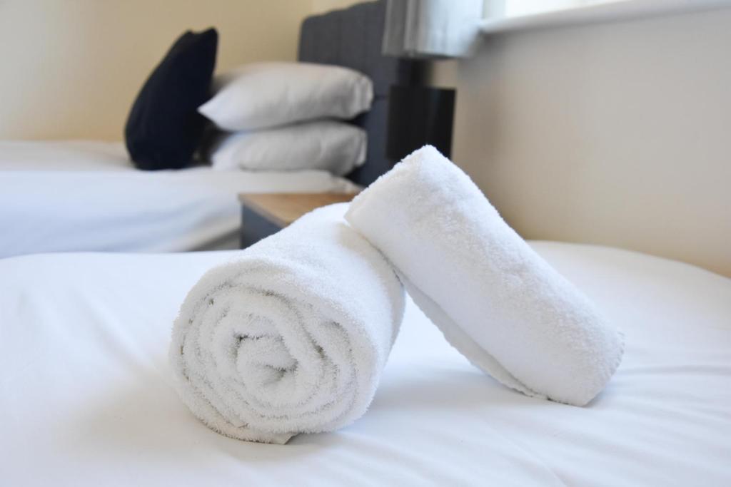 Una toalla blanca sobre una cama en Queens Lodge - Beautiful Modern House with Free Parking - Marvello Properties en Norwich