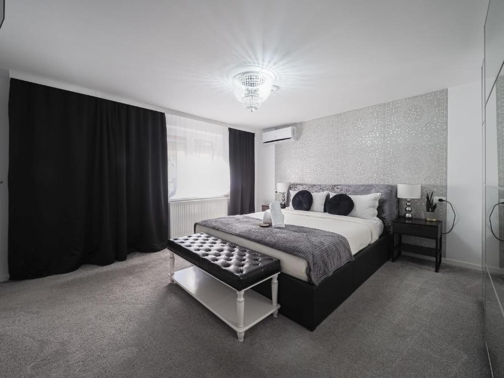 um quarto preto e branco com uma cama e um banco em For You Apartments Gold & Silver em Sibiu