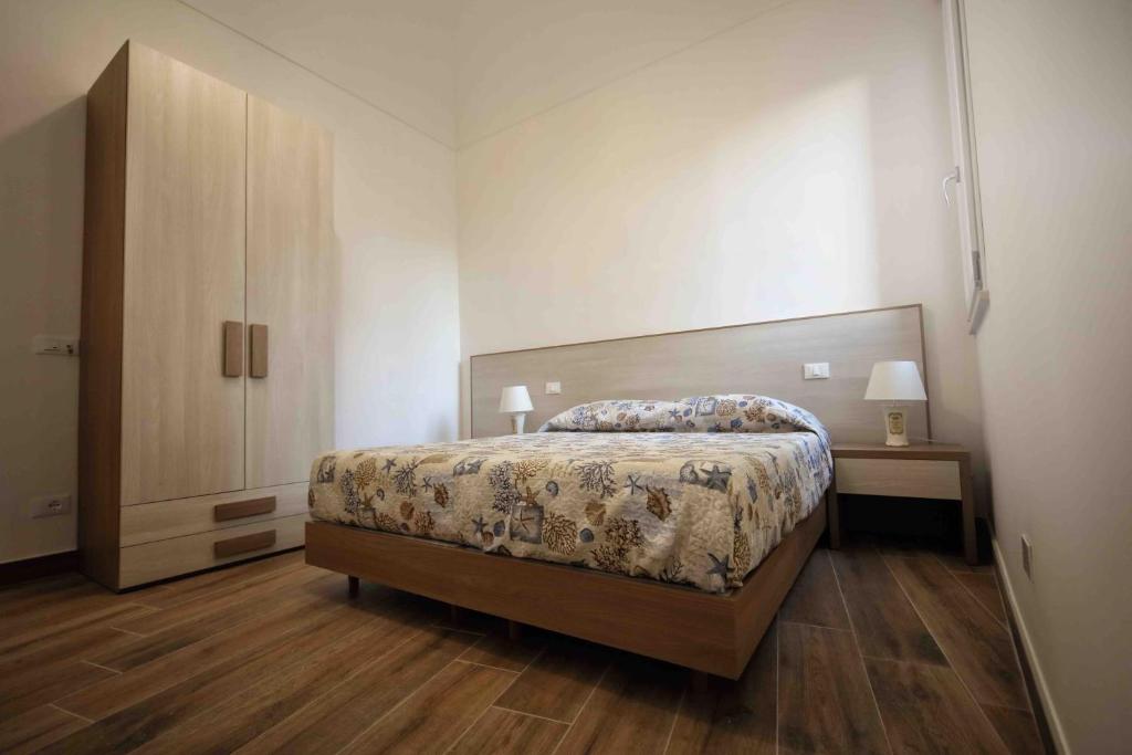 Schlafzimmer mit einem Bett und Holzboden in der Unterkunft Madrice 66 Central Rooms in Favignana