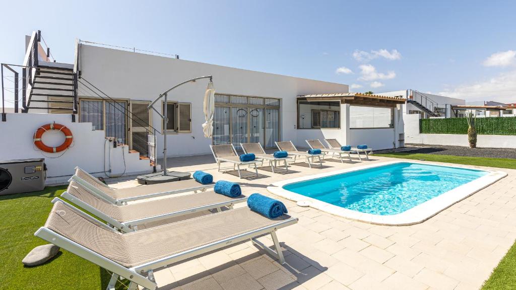 a swimming pool with chairs and a house at Luxury Villa Cindy in Caleta De Fuste