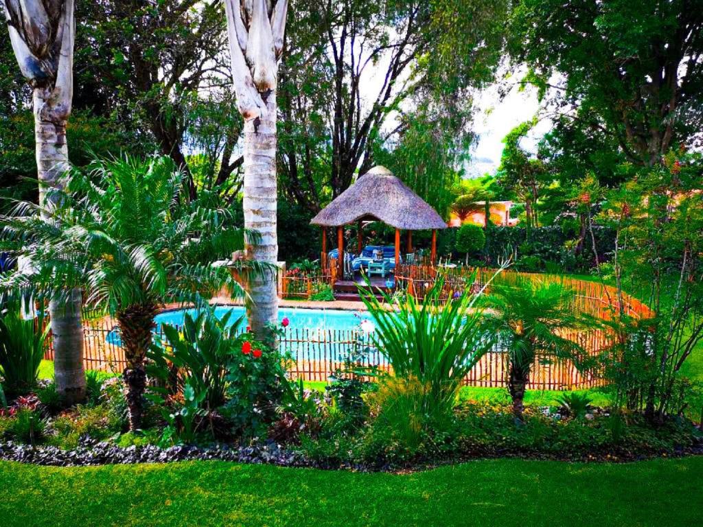 a garden with a swimming pool and a gazebo at Dublin Guest House in Sabie