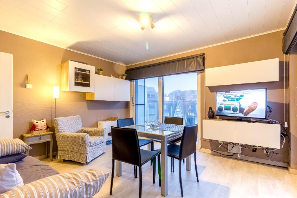 a living room with a dining room table with a television at Edelweiss 0407 in Middelkerke