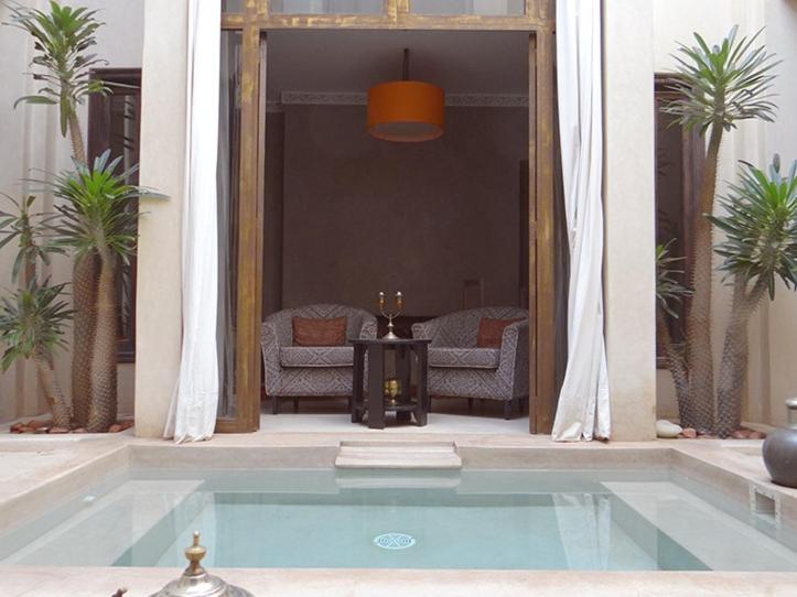 uma piscina numa sala de estar com palmeiras em Riad Vanilla Sma & Spa em Marraquexe