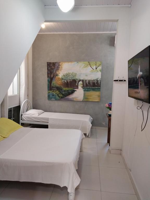 Habitación con 2 camas y una pintura en la pared. en Pousada Cantinho da Tia Sandra- suite 7, en São Francisco do Sul