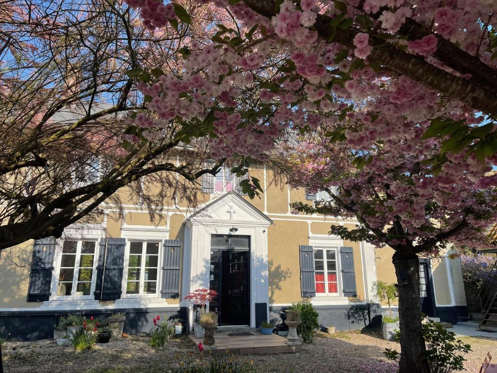 een geel huis met een bloeiende boom ervoor bij Au Presbytère de Saigneville in Saigneville