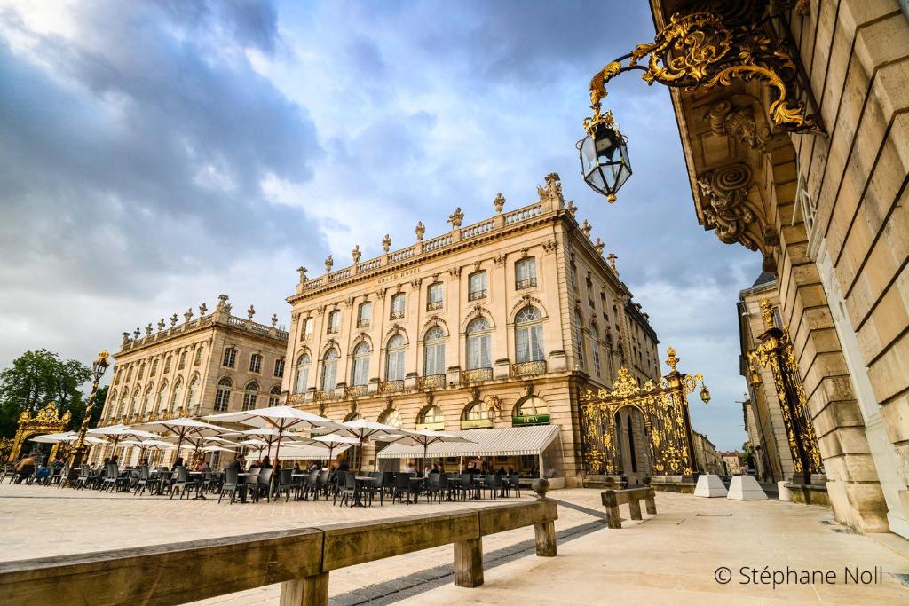 ナンシーにあるGrand Hotel De La Reine - Place Stanislasのテーブルと椅子が前に置かれた大きな建物