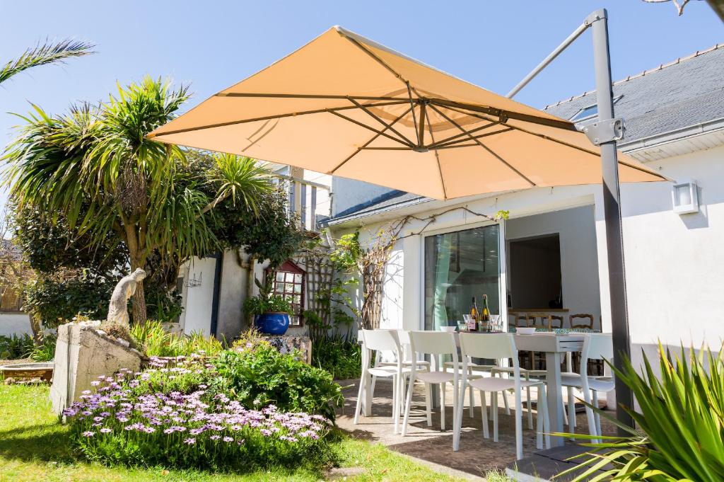 a table and chairs under an umbrella in a garden at Kan ar Moor et sa vue Mer exceptionnelle! in Pouldreuzic