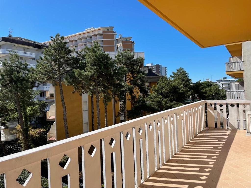 biała balustrada na balkonie z drzewami i budynkami w obiekcie Lucerna A14 w Lignano Sabbiadoro