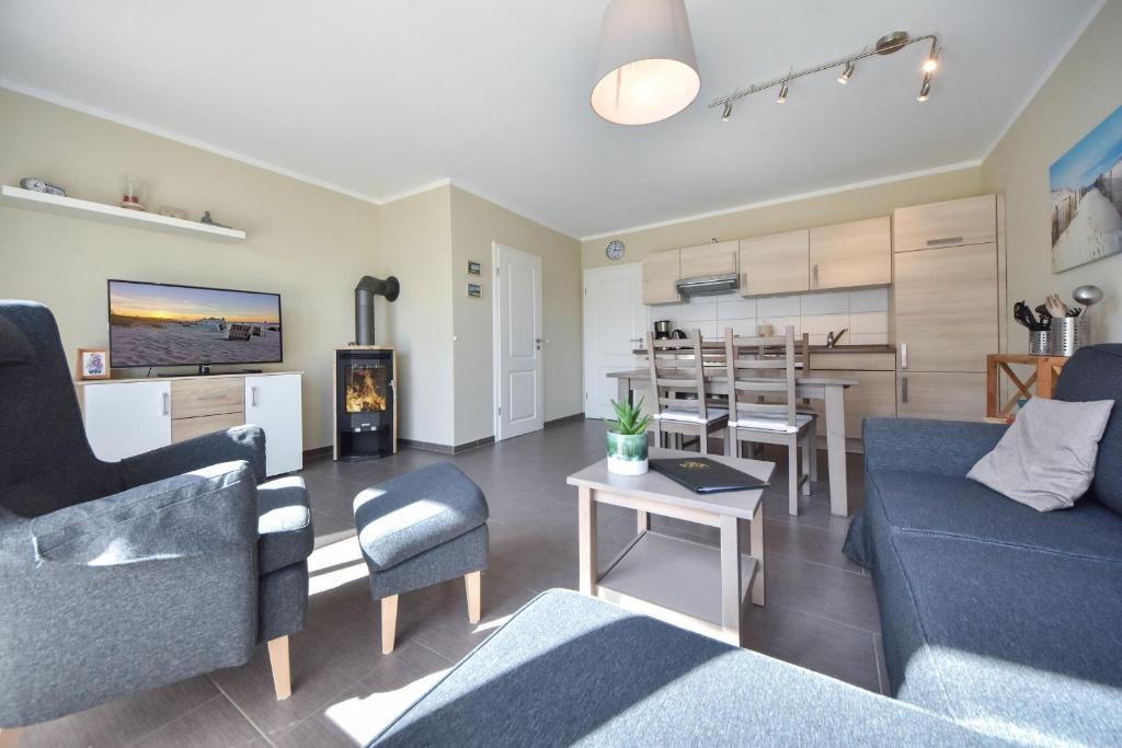 a living room with a blue couch and a kitchen at Ferienhaus Sonneninsel 5c in Korswandt