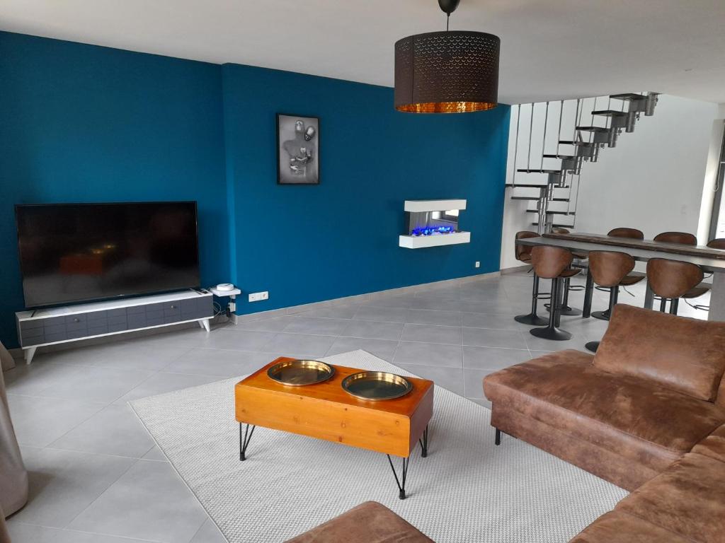 a living room with a couch and a tv and a table at Appartement moderne et spacieux in Sedan