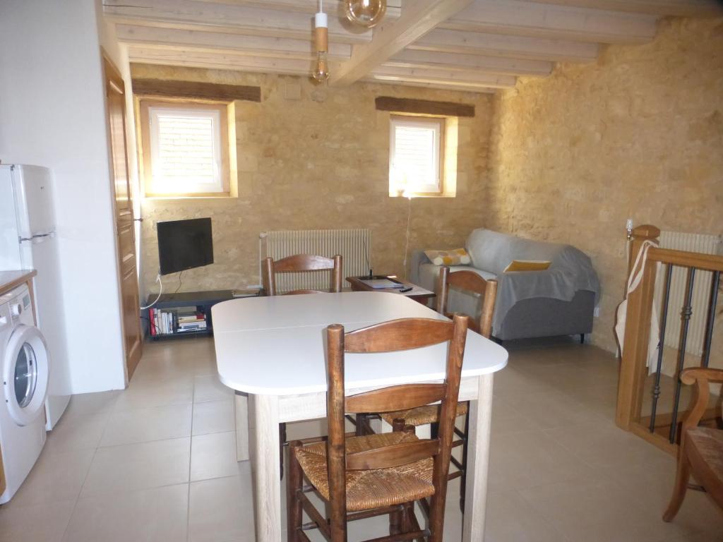 cocina y sala de estar con mesa blanca y sillas en Gîte la grange, en Domme