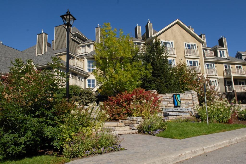 a large apartment building with a garden in front of it at Ermitage du Lac in Mont-Tremblant