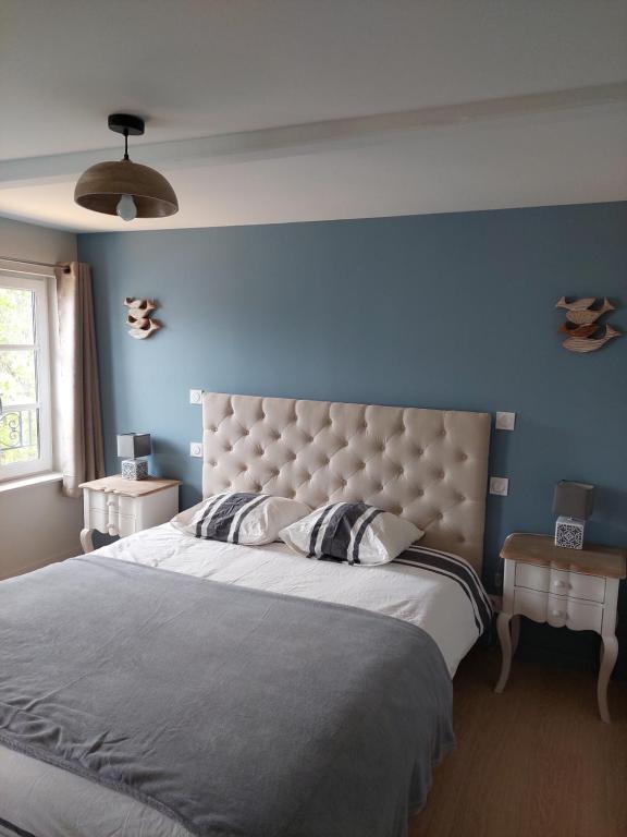 une chambre avec un grand lit avec un mur bleu dans l'établissement Un brin de fantaisie dans le centre de Honfleur, à Honfleur