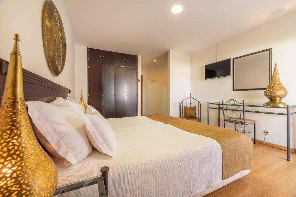 a bedroom with a large white bed and a television at Hotel Vale Da Telha in Aljezur