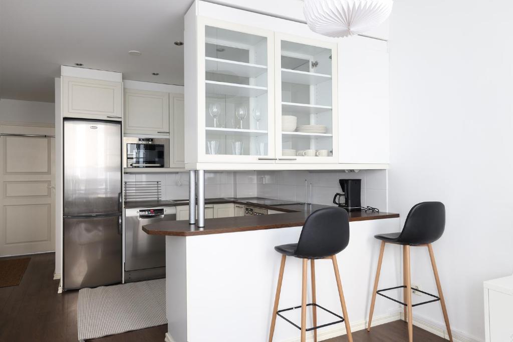 a kitchen with white cabinets and two bar stools at 2ndhomes Cozy 44m2 1BR home with best location in Kamppi! in Helsinki