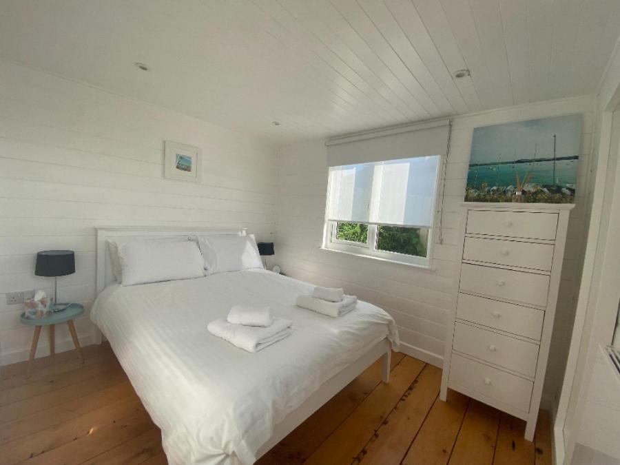 a white bedroom with a bed and a window at The Pod in Kingsbridge