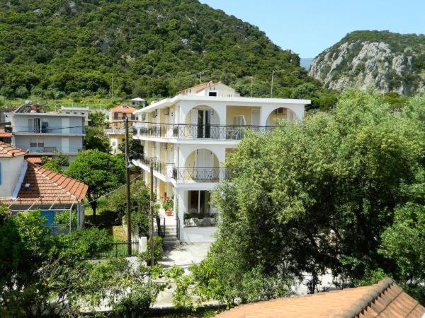 uma grande casa branca com uma montanha ao fundo em ARISTON APARTMENTS em Poros