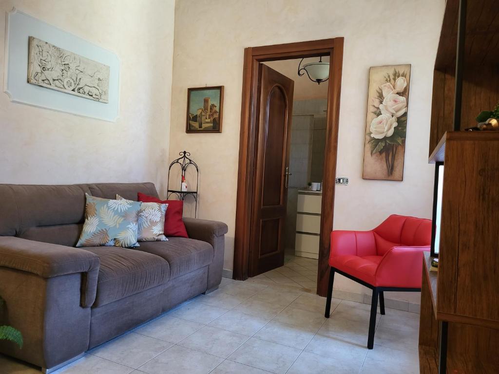 uma sala de estar com um sofá e uma cadeira vermelha em Appartamento Relax al centro Alloggio turistico em Viterbo