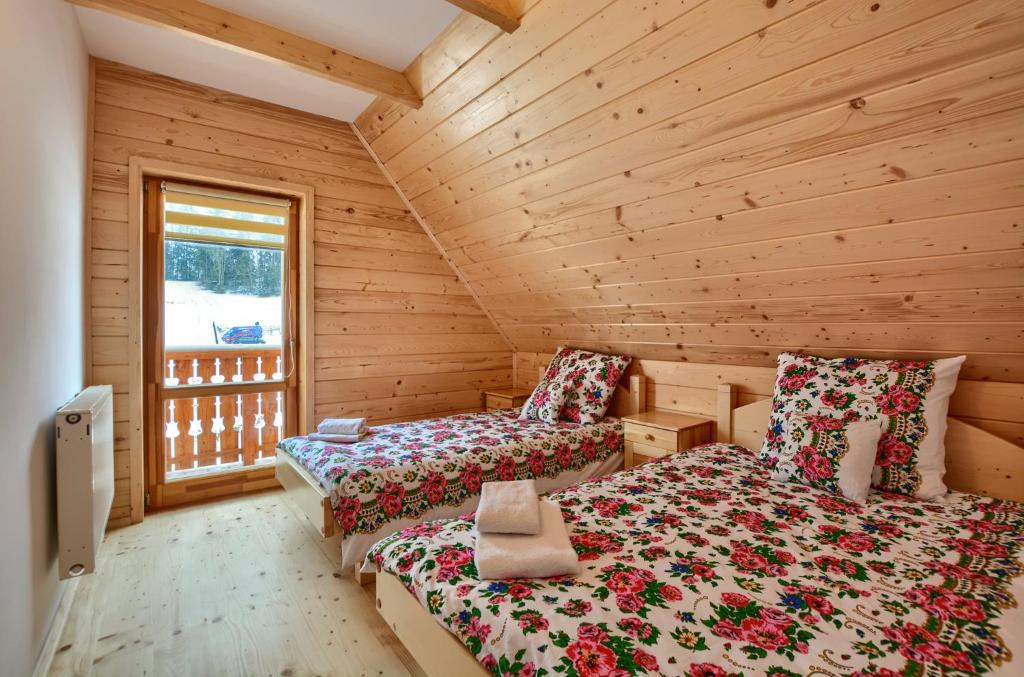 a bedroom with two beds in a log cabin at Domki Stochowa Śleboda in Bukowina Tatrzańska