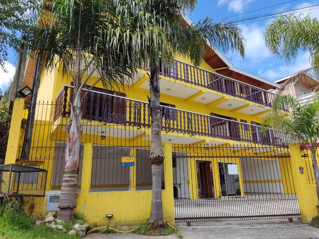 una casa amarilla con dos palmeras delante en Pousada Campos de Paiva, en Campos do Jordão