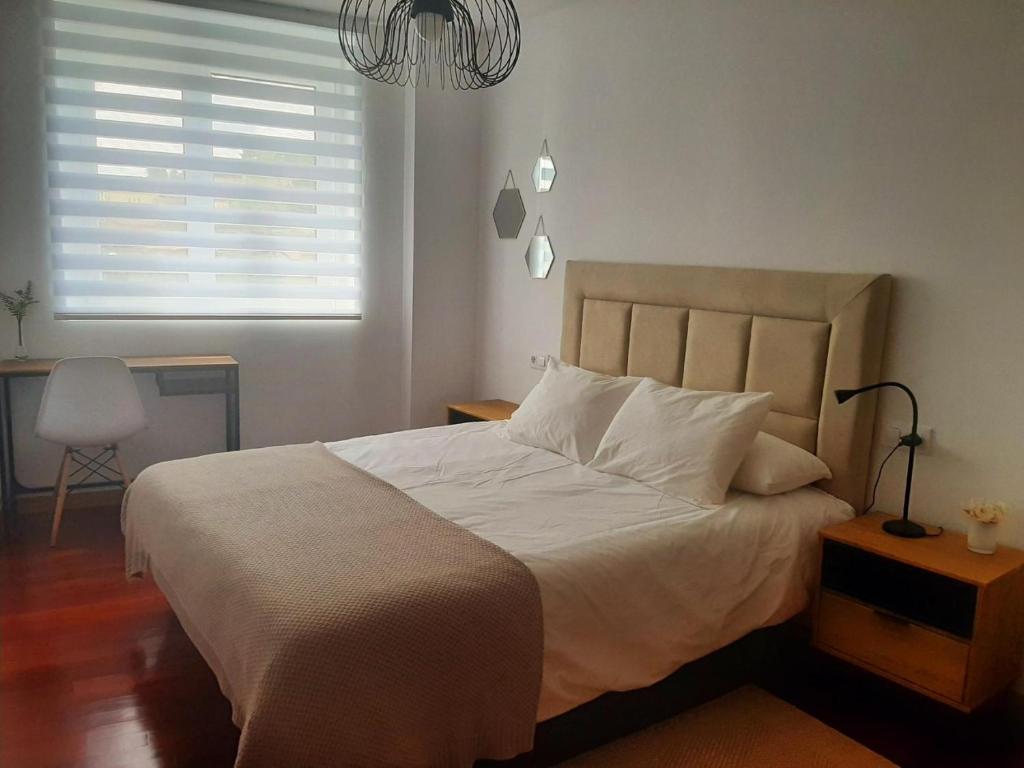 a bedroom with a large white bed with a window at Apto. en zona tranquila próximo a Santiago de C. in Brion