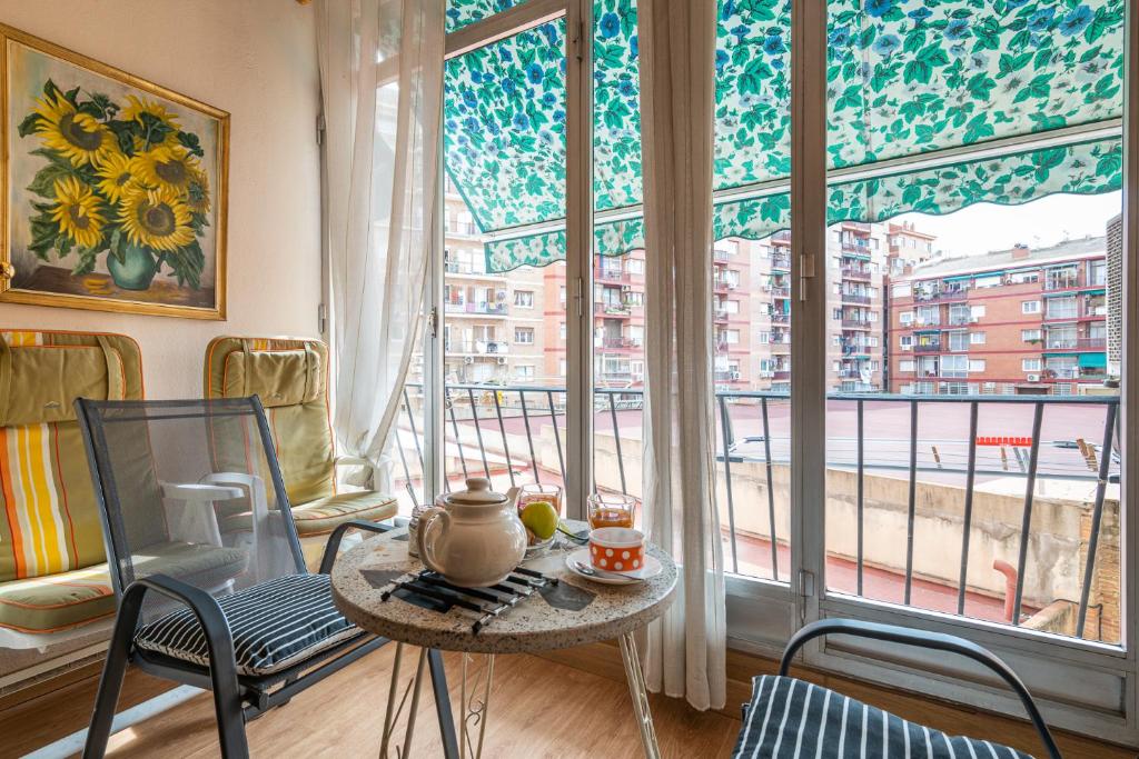 Zimmer mit einem Tisch und Stühlen sowie einem großen Fenster in der Unterkunft Flat Meridiana in Barcelona