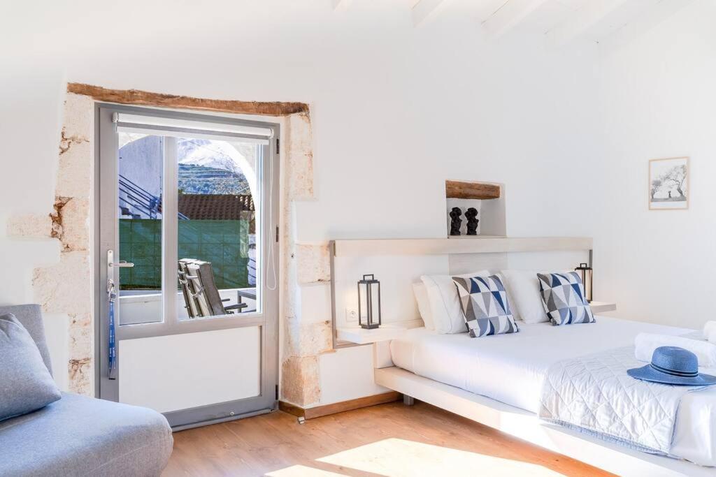 een witte slaapkamer met een bed en een raam bij Green Dia's Mansion in Arménoi