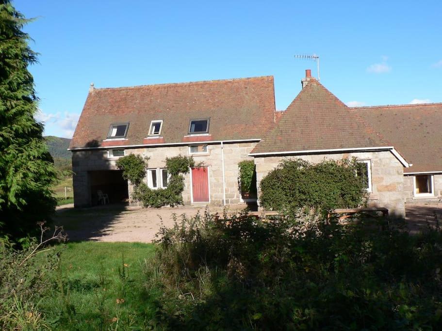 a large brick house with a red door at Tornacraig 8 Person Country House on Royal Deeside in Aboyne