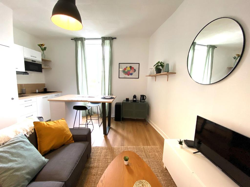 a living room with a couch and a table and a mirror at Confortable T2 sur les rives de la Charente in Angoulême