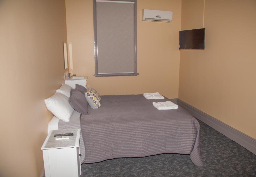 a hotel room with a bed and a mirror at Hotel Cessnock in Cessnock