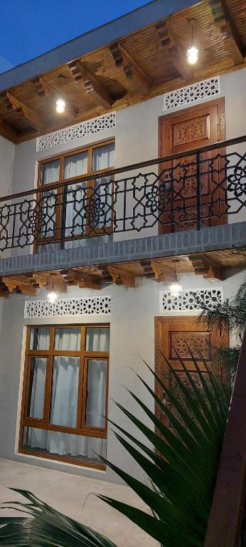 ein weißes Gebäude mit einem Balkon und einer Palme in der Unterkunft Bukhara Baraka Boutique Hotel in Buxoro