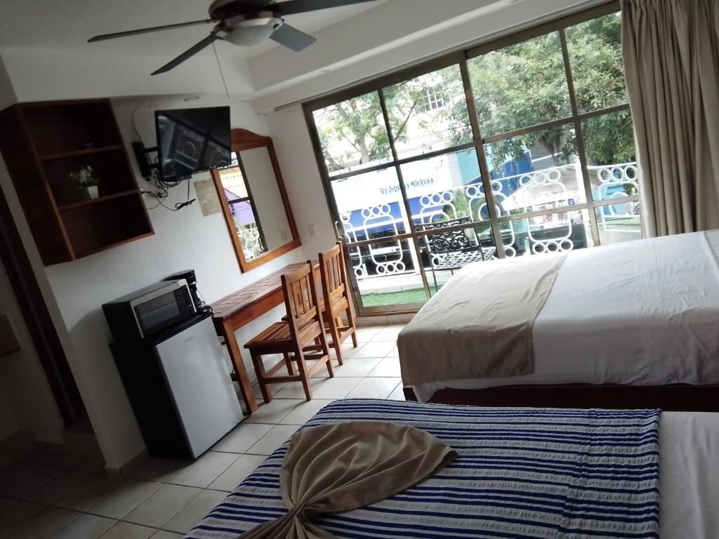 プラヤ・デル・カルメンにあるCASA BARKAのベッド2台とテレビが備わるホテルルームです。