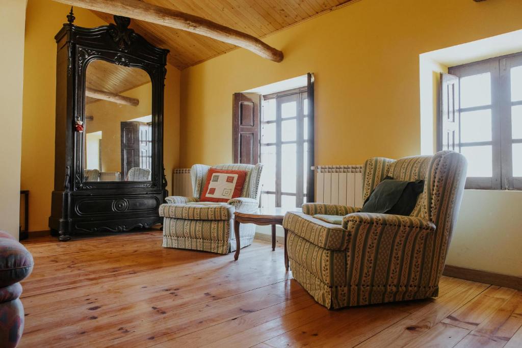 a living room with two chairs and a mirror at Casa de la Era, grande, de adobe, con patio y bodega in Fontanil de los Oteros