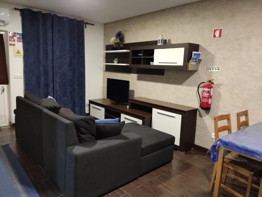 ein Wohnzimmer mit einem Sofa und einem Schreibtisch mit einem TV in der Unterkunft Casa de férias e fins de semana, 5 in Esposende