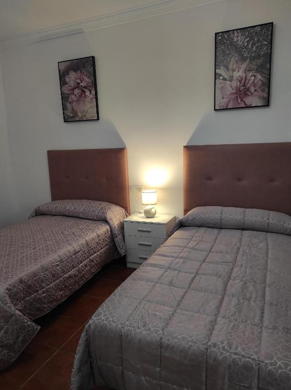 Un dormitorio con dos camas y una mesa con lámpara. en Casa Rural Moreno, en Setenil