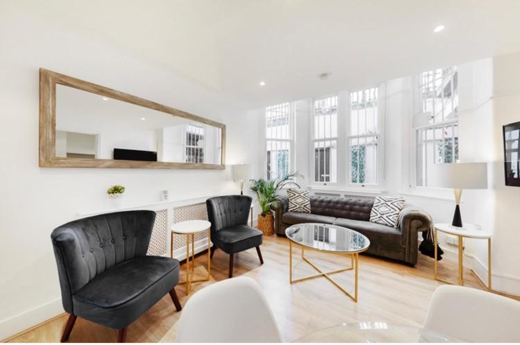 ein Wohnzimmer mit einem Sofa, Stühlen und einem Spiegel in der Unterkunft Stunning Kensington apartment in London