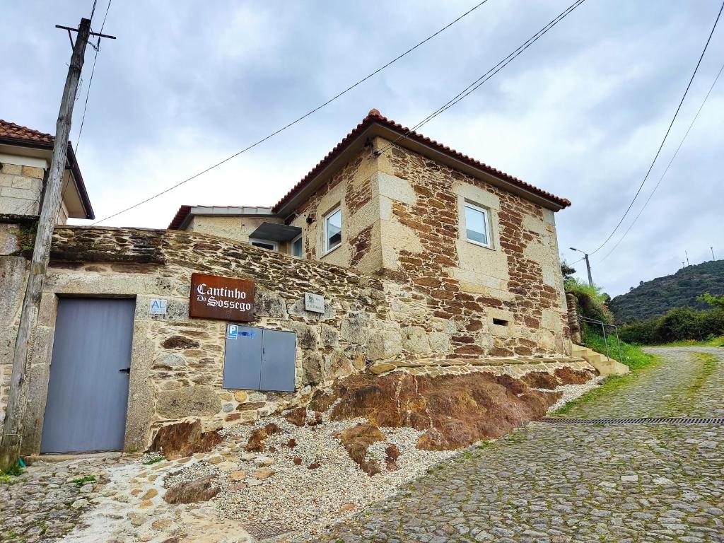 un bâtiment en pierre avec un panneau sur son côté dans l'établissement Cantinho do Sossego, à Vila Nova de Cerveira