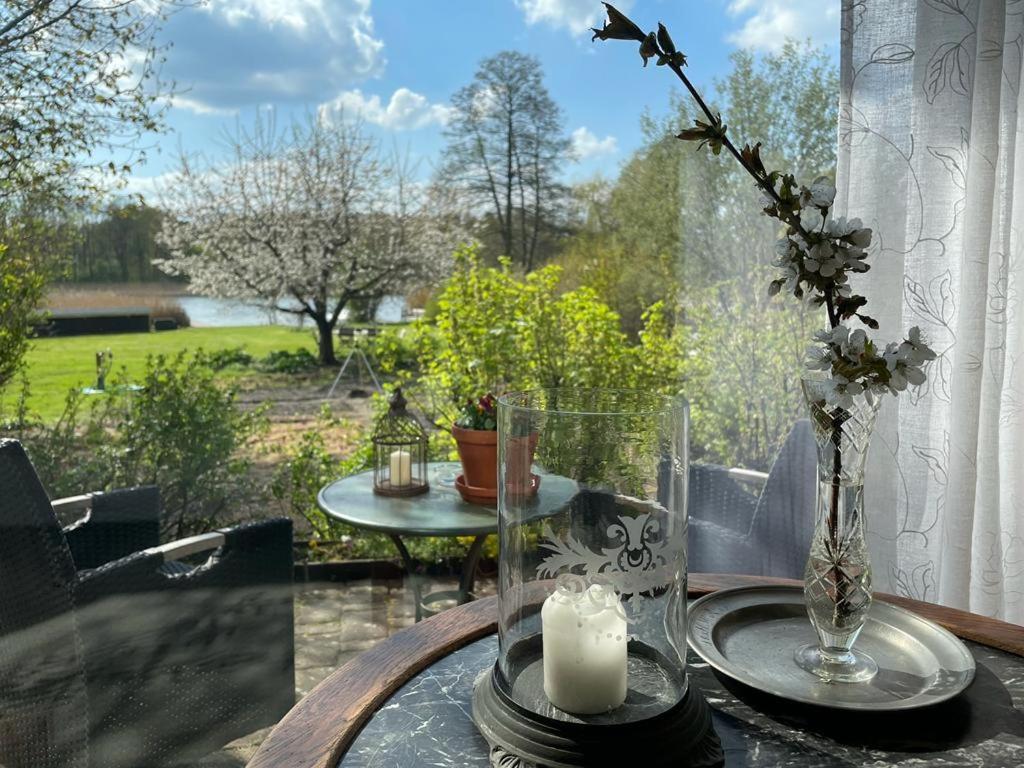 une table avec une bougie et un vase en verre avec des fleurs dans l'établissement Ars Vivendi, à Strasen