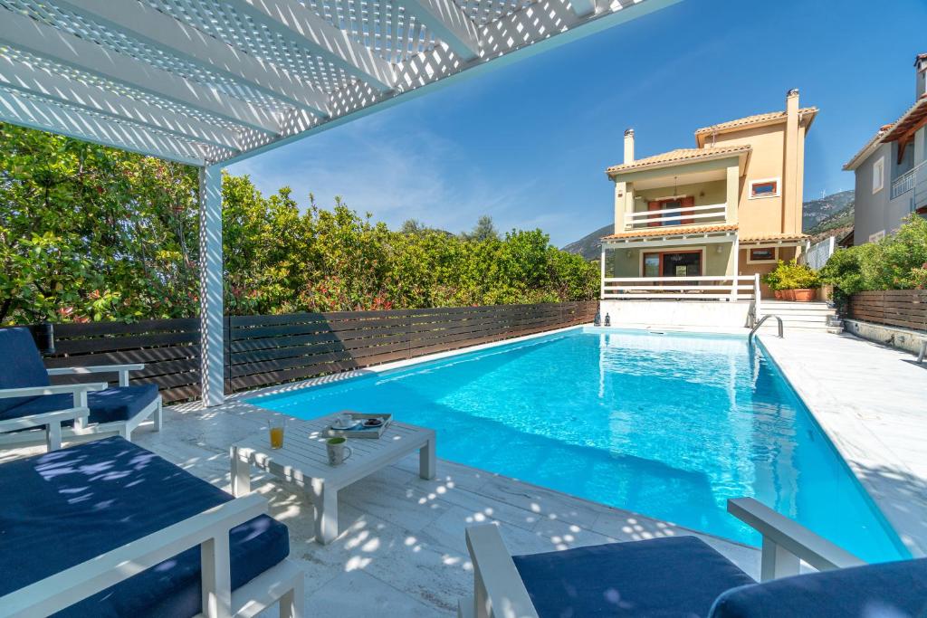 a swimming pool with a pergola and a house at SUN VILLA GLYFADA in Glyfada Fokidas