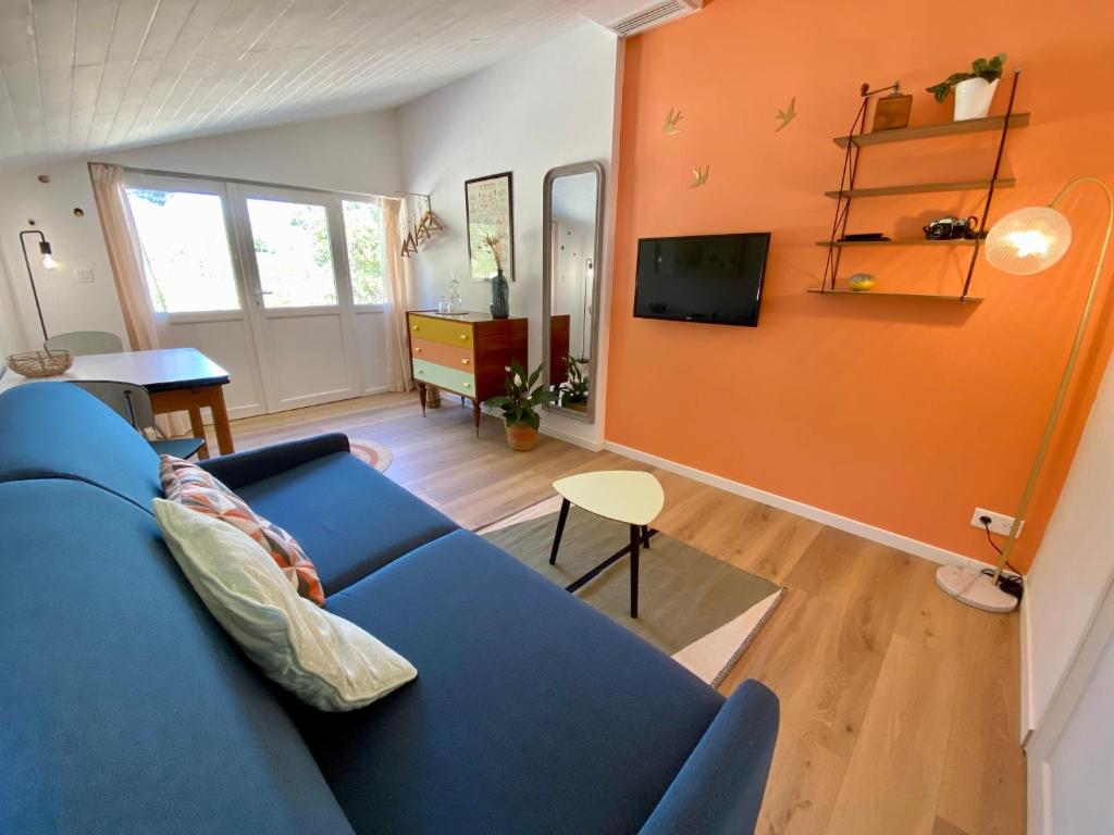 a living room with a blue couch and an orange wall at Chambre de charme indépendante proche Uzès in Fontarèches