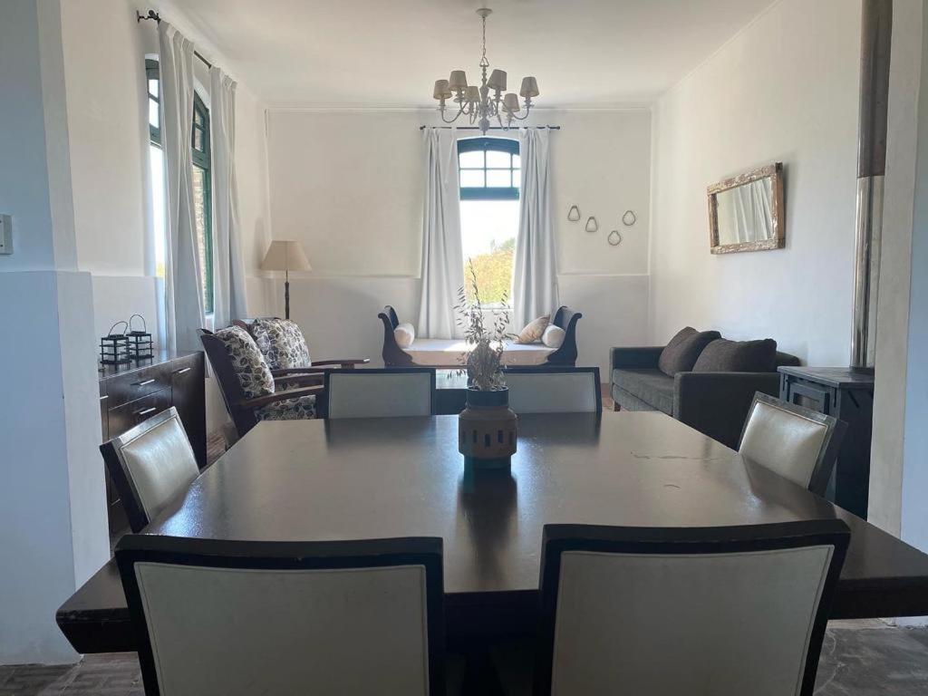 a dining room and living room with a table and chairs at Casa de campo San Agustín in Tandil