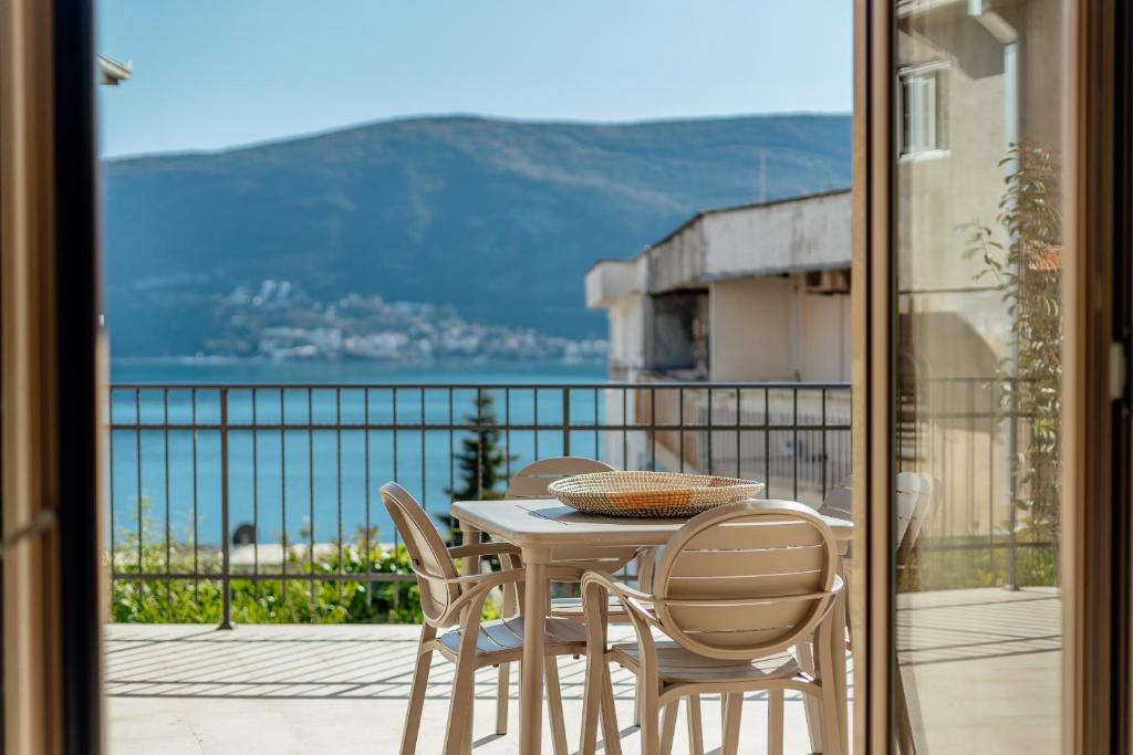 un tavolo e sedie su un balcone con vista sull'oceano di Boka Apartment 6 a Herceg-Novi